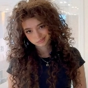 Girl with long curly hair giving a smug, knowing smirk.