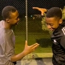 Two men laughing and high-fiving each other in a candid outdoor setting.