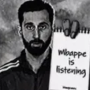 A bearded man holds a notepad with the text Mbappe is listening written on it.