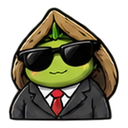 A green creature wearing a black suit, red tie, and dark sunglasses with a hood over its head.