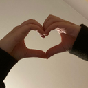 Hands forming a heart shape against a plain background.