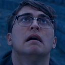 Man with glasses looking upward with a shocked and fearful expression.