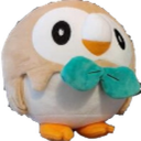A round, tan and white bird plushie with a teal bowtie looking forward.