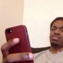 A man looking at his phone with a squinted, skeptical expression of disbelief.