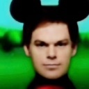 A man with a serious expression wearing black Mickey Mouse ears against a green background.