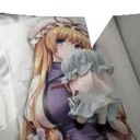 Anime girl with long hair lying in bed and hugging a small frilly plush toy.