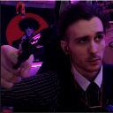 A man in a formal shirt and tie points his finger forward with a serious, judgmental expression.