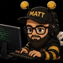 A bearded man wearing a bee-themed hat and hoodie typing on a computer keyboard with intense focus.
