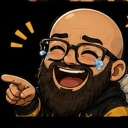 A bearded man wearing glasses laughing with his mouth wide open and tears streaming from his eyes while pointing to the side.