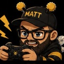 A bearded man with glasses and a cap playing a video game with an intense, angry expression.