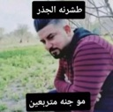 A man with a beard looking down thoughtfully with Arabic text in black boxes above and below him.