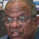 Man with glasses looking at the camera with wide, shocked eyes.
