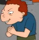 A cartoon boy with red hair and a blue shirt hunched over with a mischievous, plotting grin.