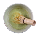 Bamboo whisk mixing vibrant green matcha tea in a white ceramic bowl.