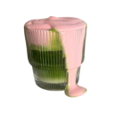 A ribbed glass filled with green matcha and topped with a thick layer of pink foam that is dripping down the side.