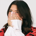 Woman covering her mouth with her hands while laughing.