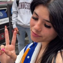 Person holding up a peace sign with eyes closed in a relaxed expression.