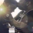 Two people sharing a tender forehead kiss in a blurry, low-resolution photograph.