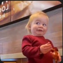 Toddler wearing a red shirt looking off-camera with a skeptical side-eye expression.