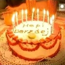 Birthday cake with lit candles and misspelled text written on the frosting.