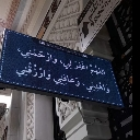 A rectangular sign with white Arabic calligraphy on a dark blue background.