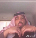 Man wearing a red and white ghutra sticking his tongue out playfully.