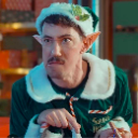 A man wearing a green elf costume and hat looks sideways with a skeptical and suspicious facial expression.