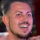 Man with a goatee smiling widely with teeth showing in a candid close-up shot.