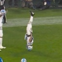A football player in a white uniform performing a backflip on a green grass field.
