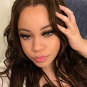 A young woman with long dark hair poses for a casual selfie with a relaxed expression.