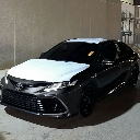 A black sedan parked in a dimly lit area with a white hood cover.