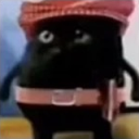 A small black creature with a skeptical expression wearing a red hat and a pink belt.