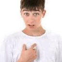 Young man pointing at his own chest with a surprised and confused expression.