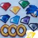 Pixel art of a blue hedgehog head surrounded by colorful diamond-shaped gems and three gold rings.