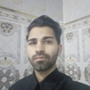 A man with a beard looking directly at the camera with a neutral and serious expression.