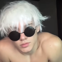 A person with white hair wearing dark circular sunglasses looking directly at the camera with a smug expression.