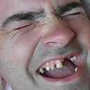 Man with a pained, squinting expression and visible teeth grimacing in discomfort.