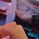 A hand holds a single square slice of yellow processed cheese in a dark room.