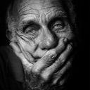 Elderly person resting their chin on their hand with a weary and disappointed facial expression.