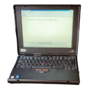 A black vintage laptop with an open screen sitting on a dark background.