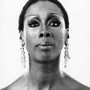 A woman with a serious, unimpressed expression stares directly forward in a black and white portrait.