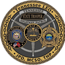 A circular law enforcement badge featuring the Tennessee state seal and various agency acronyms.