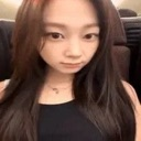 Young woman with long dark hair staring directly at the camera with a neutral, unimpressed expression.