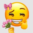 A yellow smiley face with long eyelashes and a pink bow, biting its finger while holding a small bouquet of pink tulips.