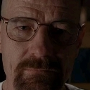 Man with glasses and a goatee looking directly at the camera with a serious, suspicious expression.