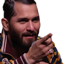 A man with a beard and patterned jacket points his finger directly forward with a serious and knowing expression.