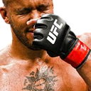 A fighter with eyes closed takes a punch to the face while wearing a black UFC glove.