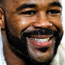 Man with a dark beard and mustache showing a wide, toothy grin.
