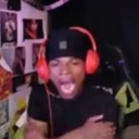 A person wearing black headphones and a black cap with their mouth wide open in a large yawn.