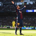 Lionel Messi stands on a soccer pitch with his arms raised high in celebration.